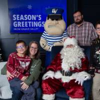 Two brothers with parents smile with Santa and Louie